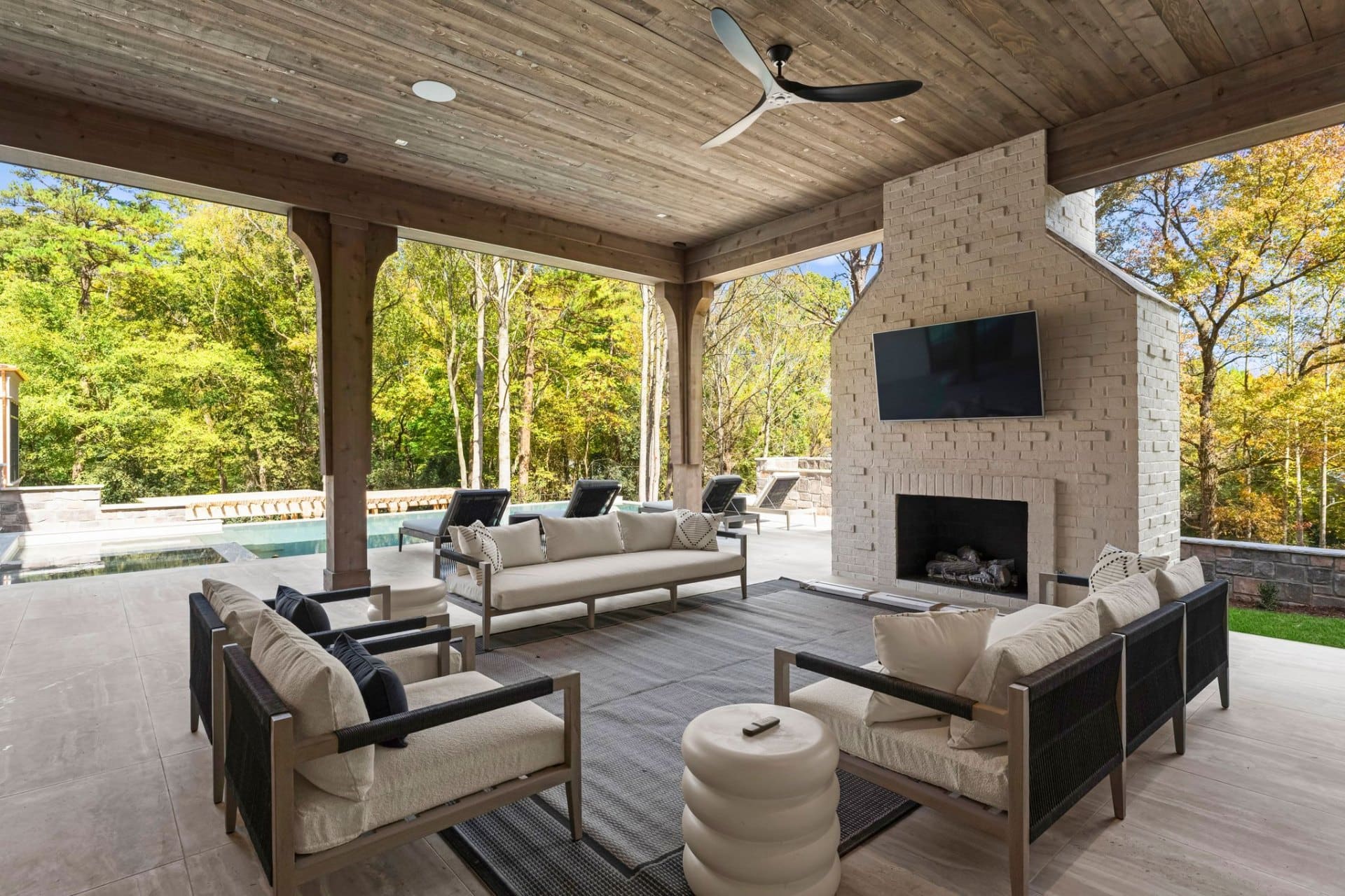 Covered lounge with brick fireplace and pool view