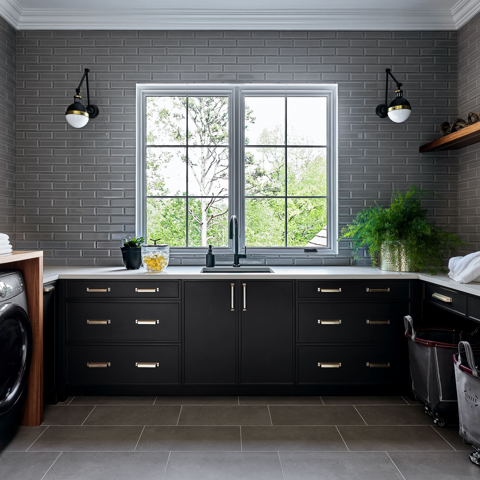 Dark laundry room with subway tile and brass hardware