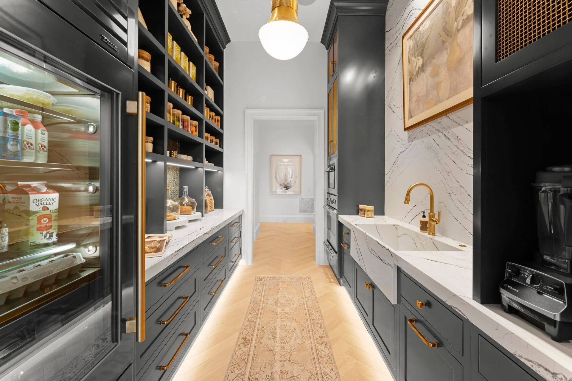 Dark pantry with marble backsplash and glass fridge